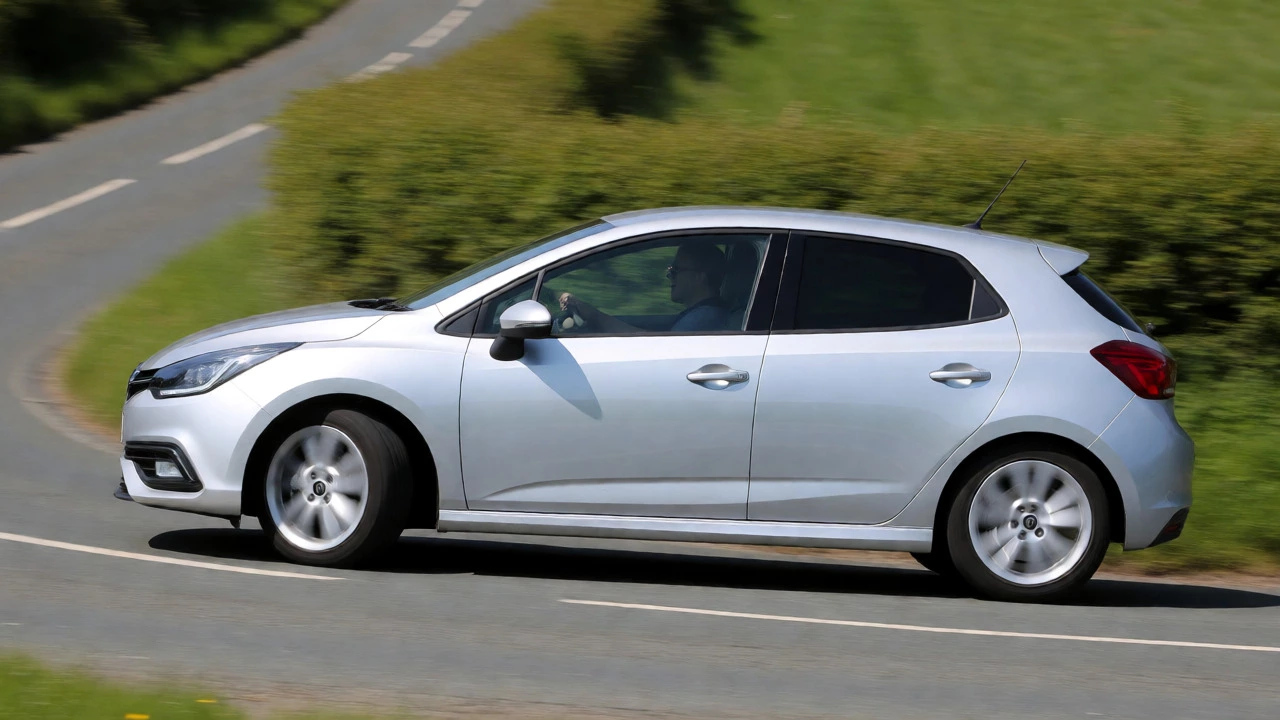 Silver hatchback cornering on a road showing controlled suspension movement and reduced body roll.